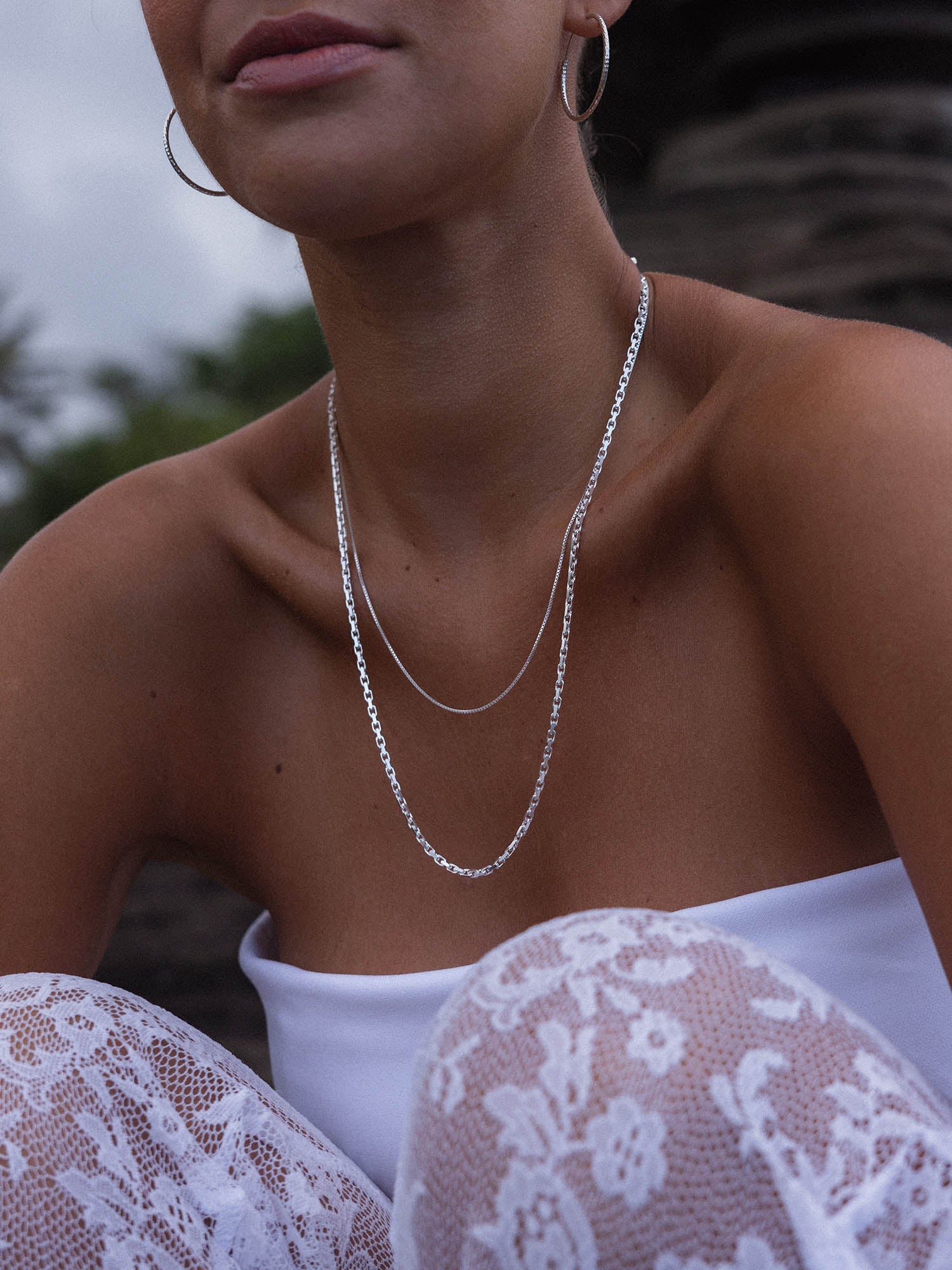 Gleam Kette aus recyceltem Silber mit schimmernder Kettenstruktur, getragen in natürlicher, eleganter Outdoor-Atmosphäre.