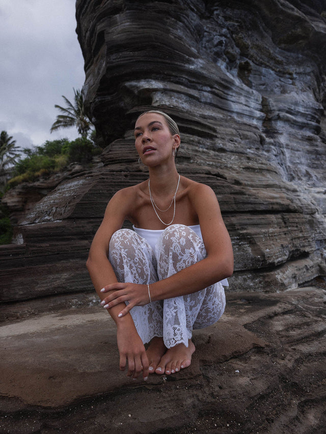 Perfection Kette aus feinem Silber mit Süßwasserperle, getragen am Strand vor vulkanischen Felsen, elegant und zeitlos von PURELEI.