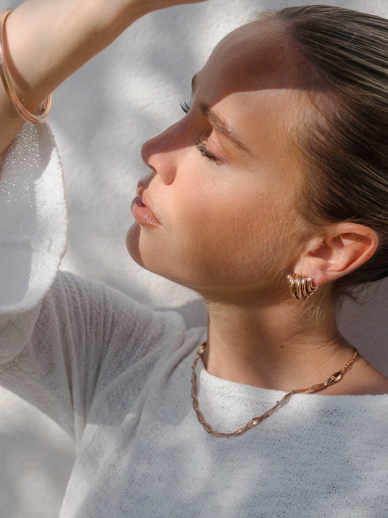 Roségoldene Kette und Creolen von PURELEI, elegant und feminin, in warmem Licht.