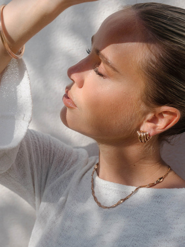 Roségoldene Kette und Creolen von PURELEI, elegant und feminin, in warmem Licht.