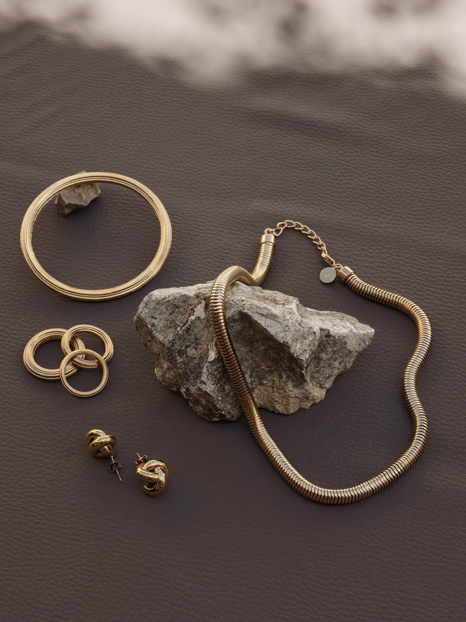 Silberne Schmuckstücke von PURELEI: Kette, Ringe und Ohrringe auf dunklem Hintergrund.