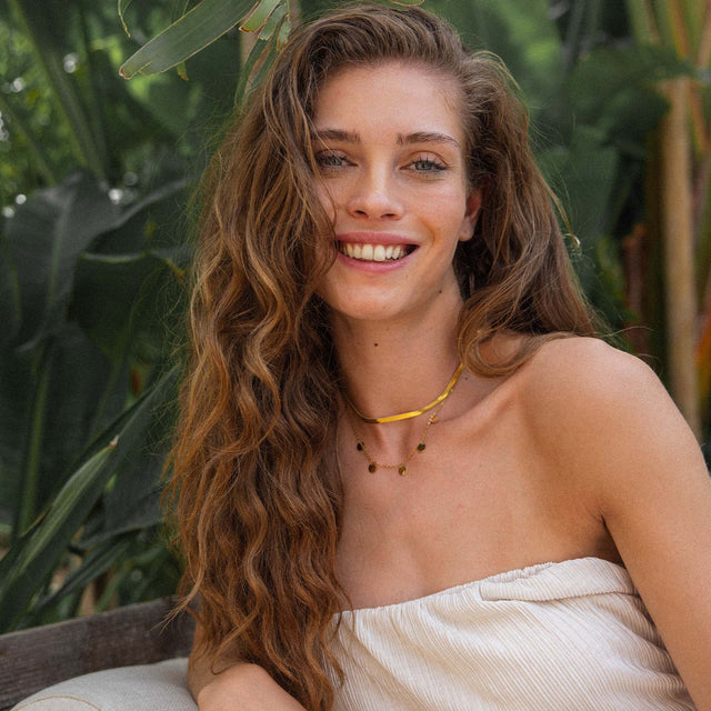 Zarte PURELEI Kette mit schwarzen Akzenten, getragen in tropischer Umgebung, strahlt natürliche Eleganz aus.