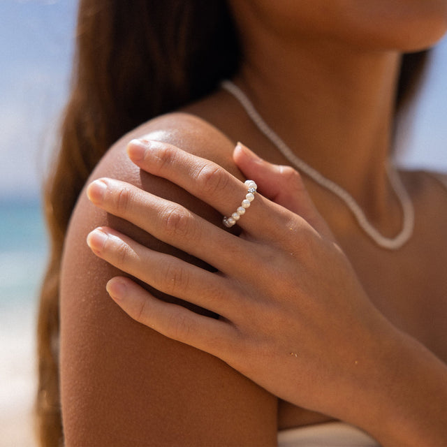 Anxiety Shiny Bloom Ring von PURELEI mit Muschelperlen und eleganter Blüte, natürliche Leichtigkeit am Strand getragen.