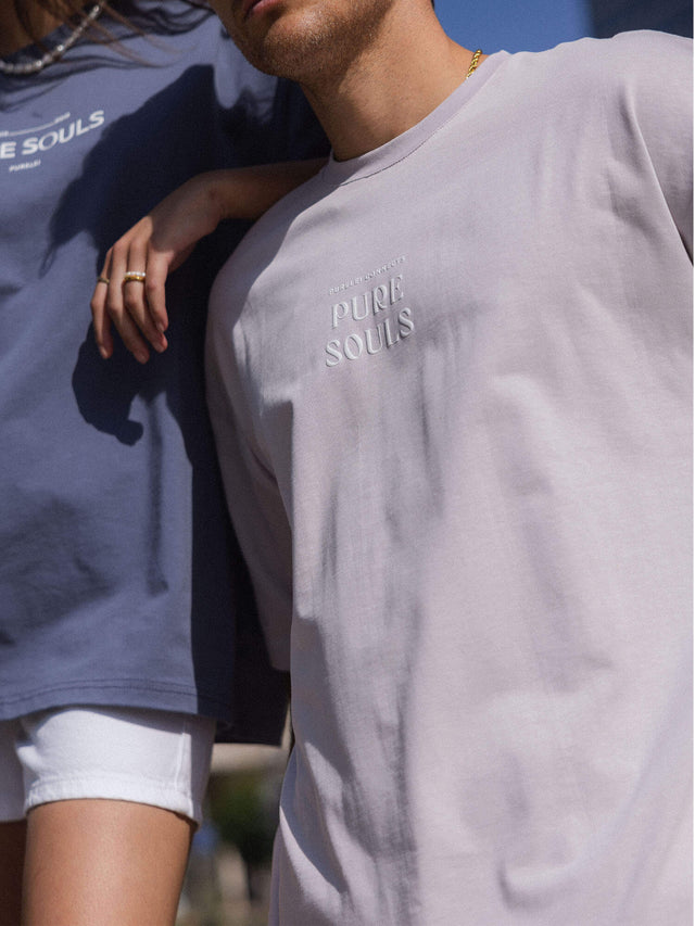 Beige und blaue T-Shirts mit PURELEI-Logo, lässig und modern in sonniger Atmosphäre.