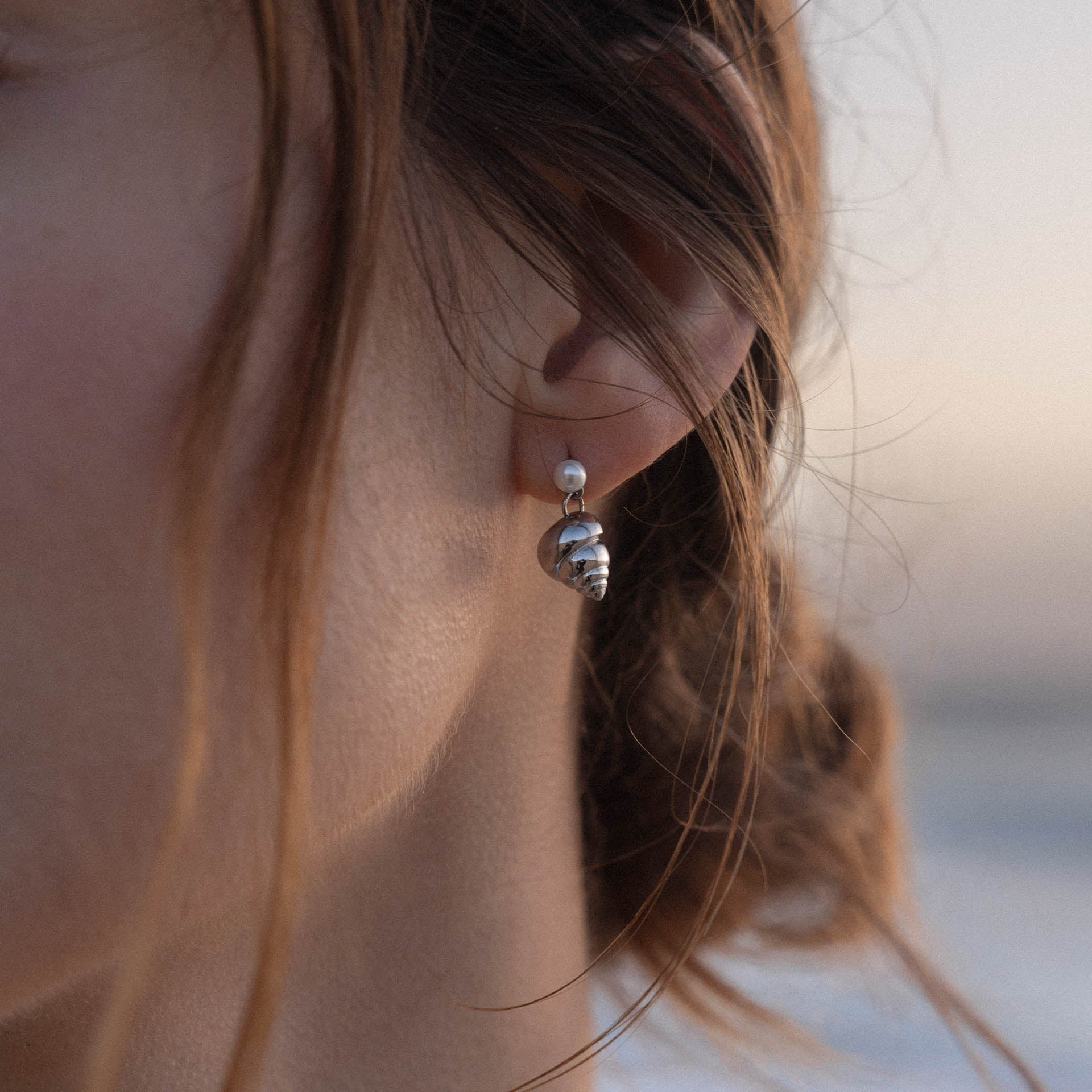 Silberne Muschel-Ohrringe mit Perle, getragen in sanfter Lichtstimmung – PURELEI.
