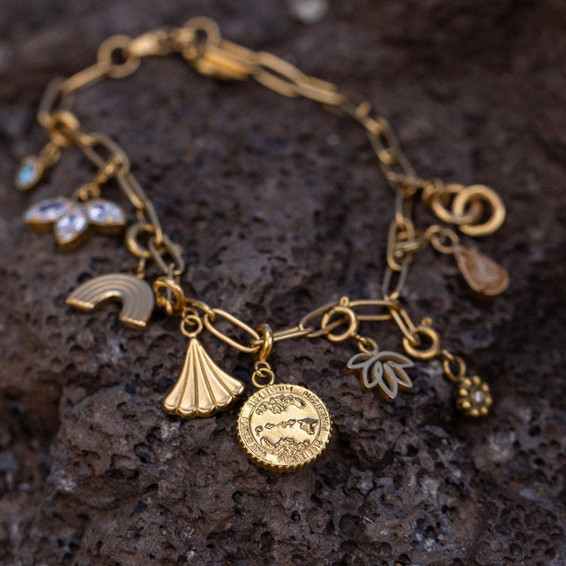 Goldenes Charm-Armband mit Muschel- und Pflanzenanhängern von PURELEI, tropische Eleganz.