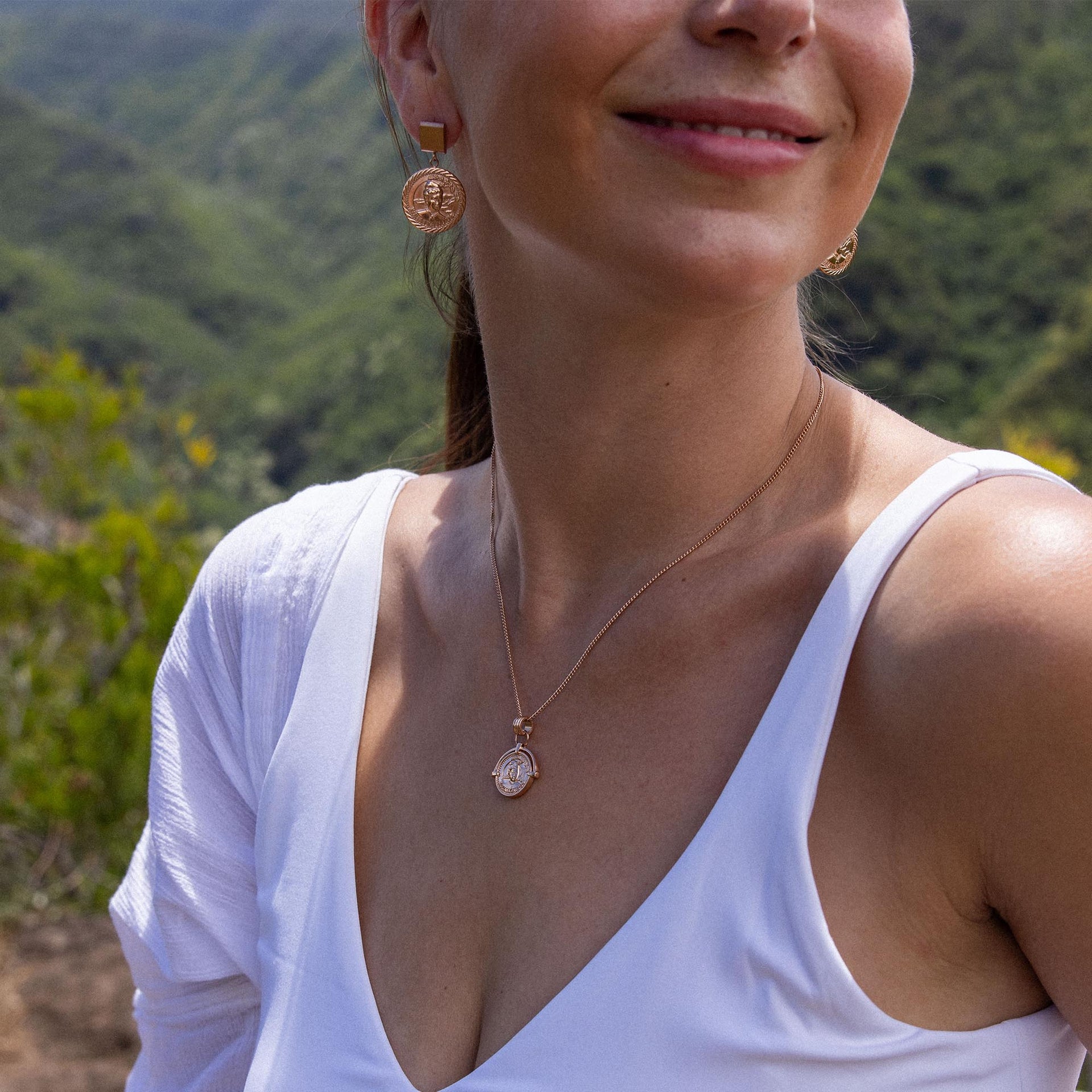 Roségoldene Ohrringe und Kette von PURELEI, elegant und feminin, umgeben von Natur.