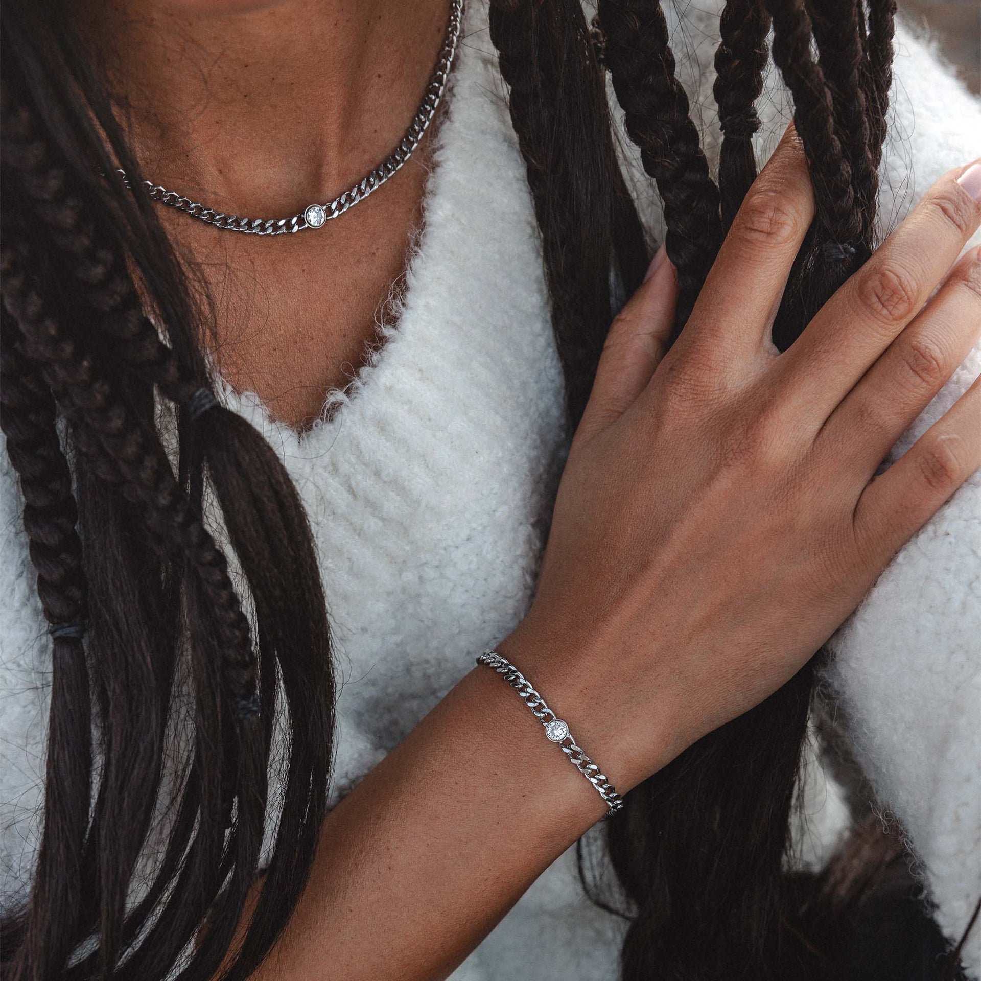Silberne Kette und Armband von PURELEI, elegant mit glänzendem Detail, getragen auf weichem Pullover.