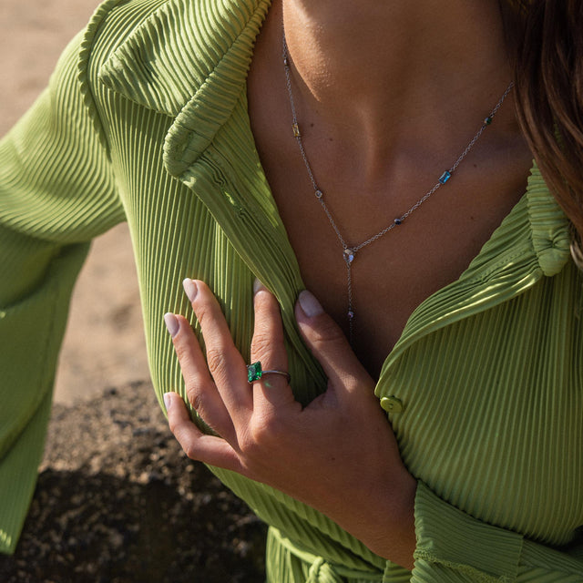 Zarte goldene Kette und Ring mit grünen Steinen, getragen in tropischer Stimmung – PURELEI.