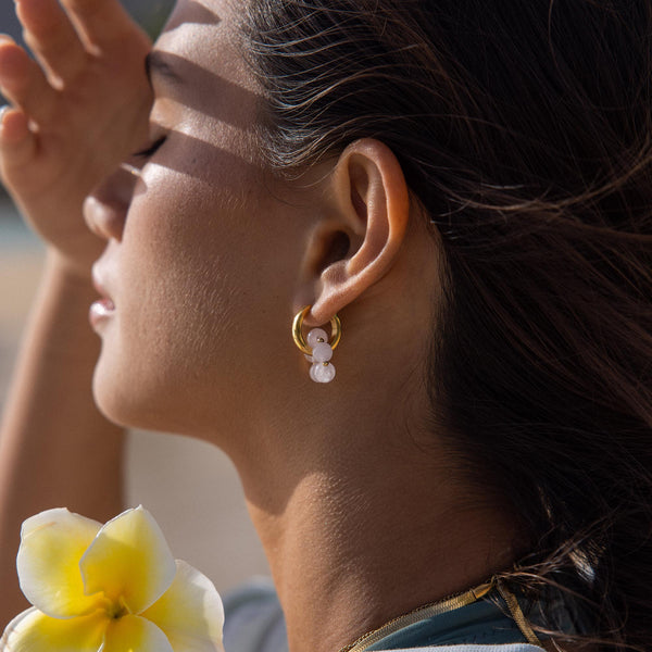 Goldene Creolen mit weißen Perlen, PURELEI, in warmem Licht, elegant und feminin.