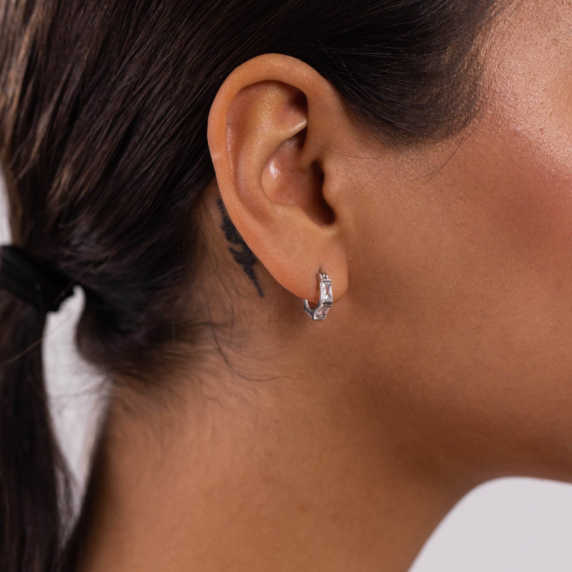 Silberne Creolen mit klaren Steinen, elegant am Ohr getragen, inspiriert von PURELEI.