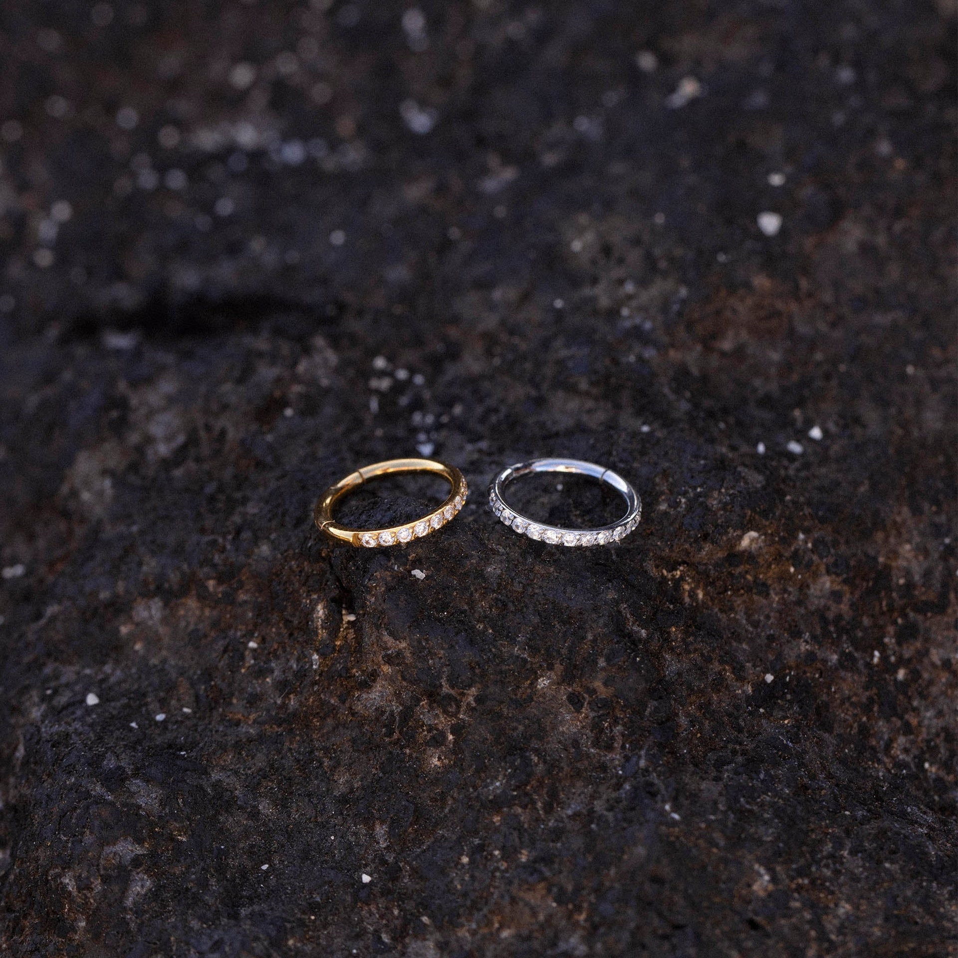 Glow Piercing in Gold und Silber mit funkelnden Zirkonia auf dunklem Lavagestein, PURELEI Nickelfrei.