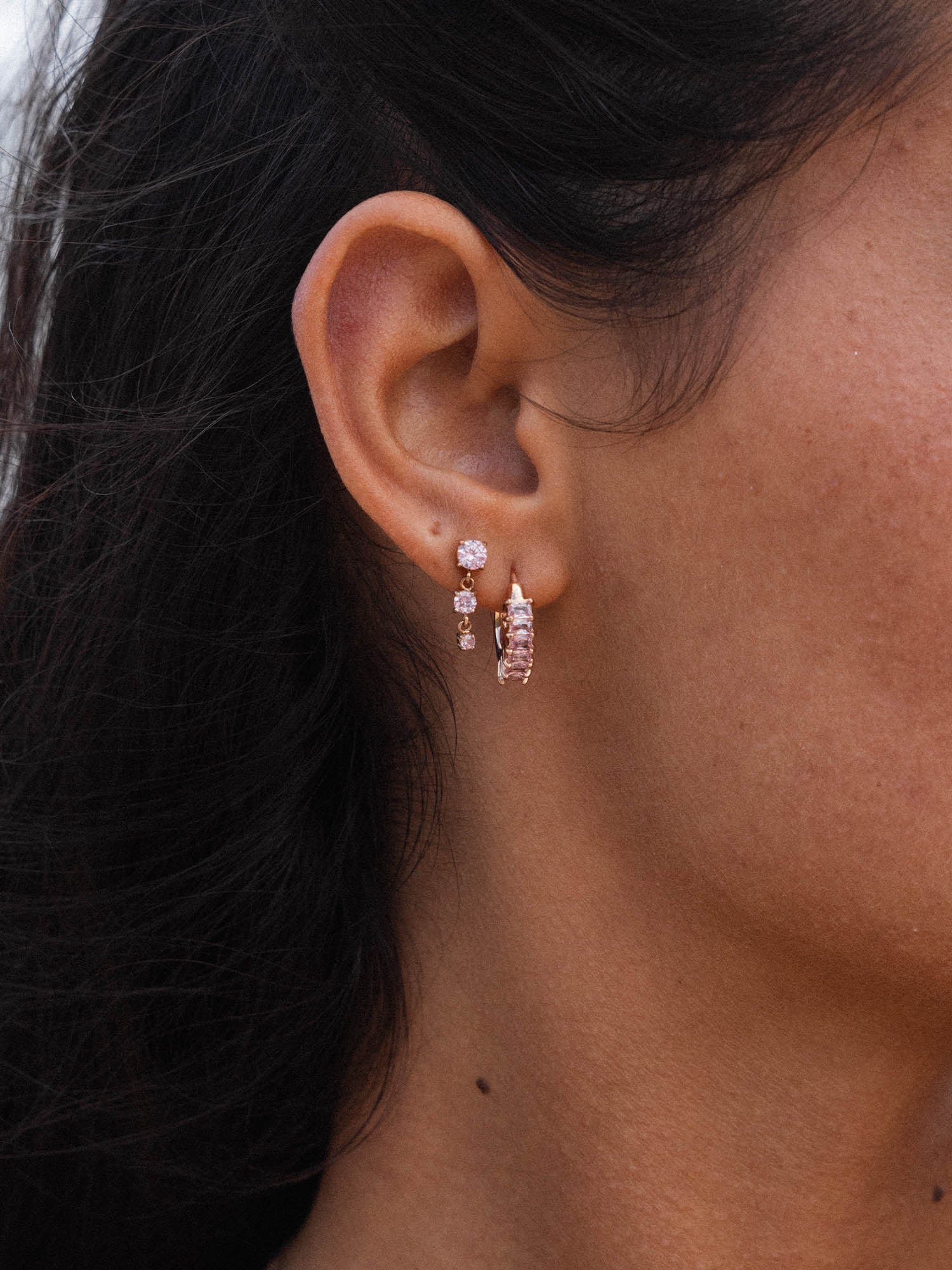 Roségoldene Ohrringe mit funkelnden Details, getragen in einem natürlichen Licht, PURELEI.