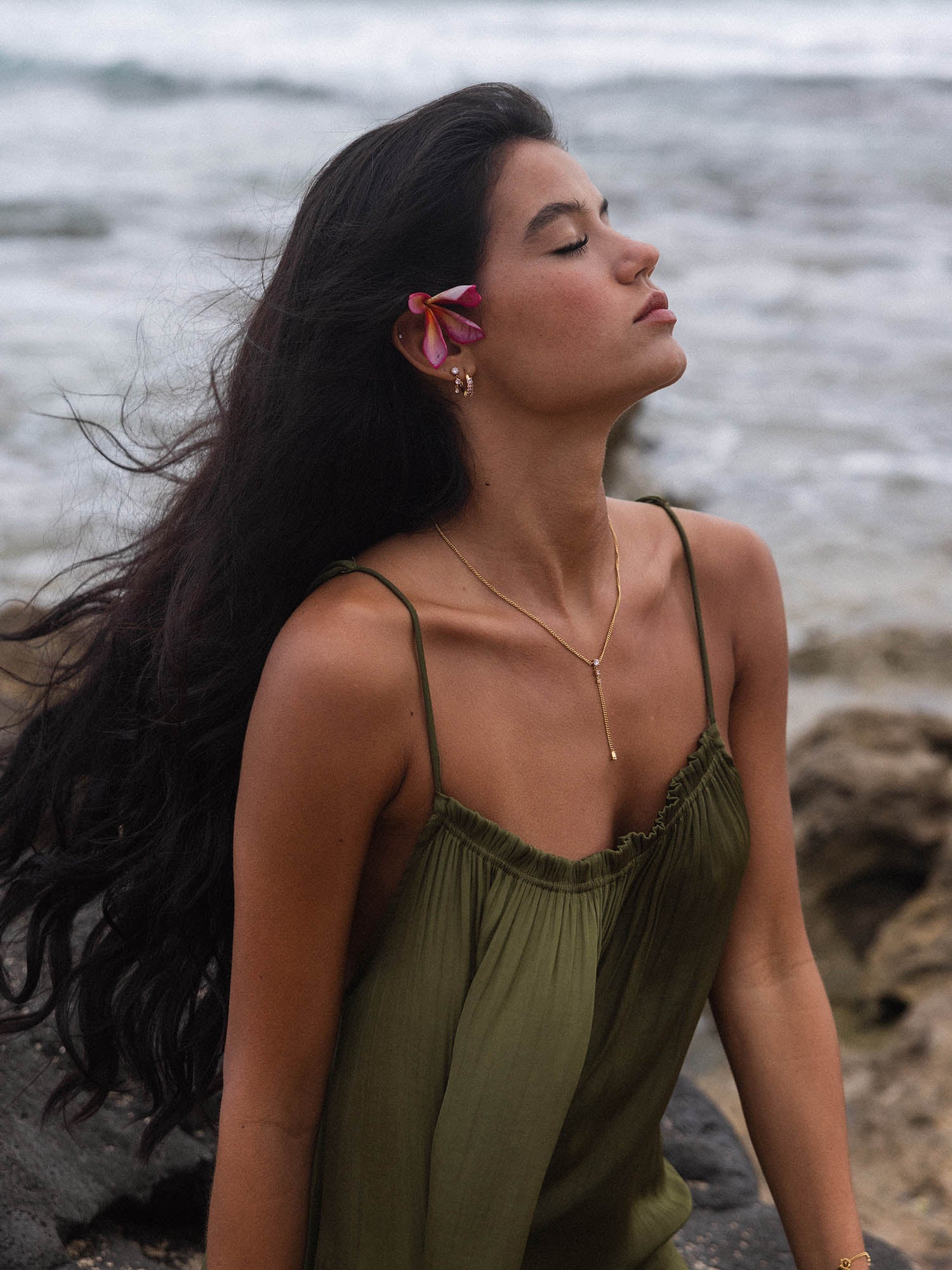 Elegante PURELEI Kette mit zartem Anhänger, getragen am Strand, umgeben von tropischer Atmosphäre.