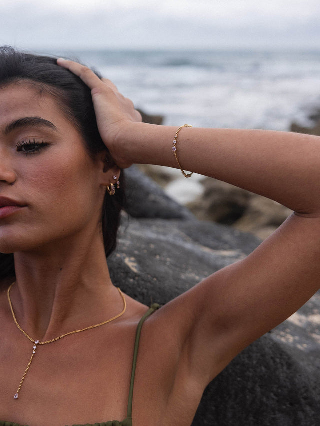 Roségoldene PURELEI Kette und Armband mit funkelnden Details, getragen am Strand.