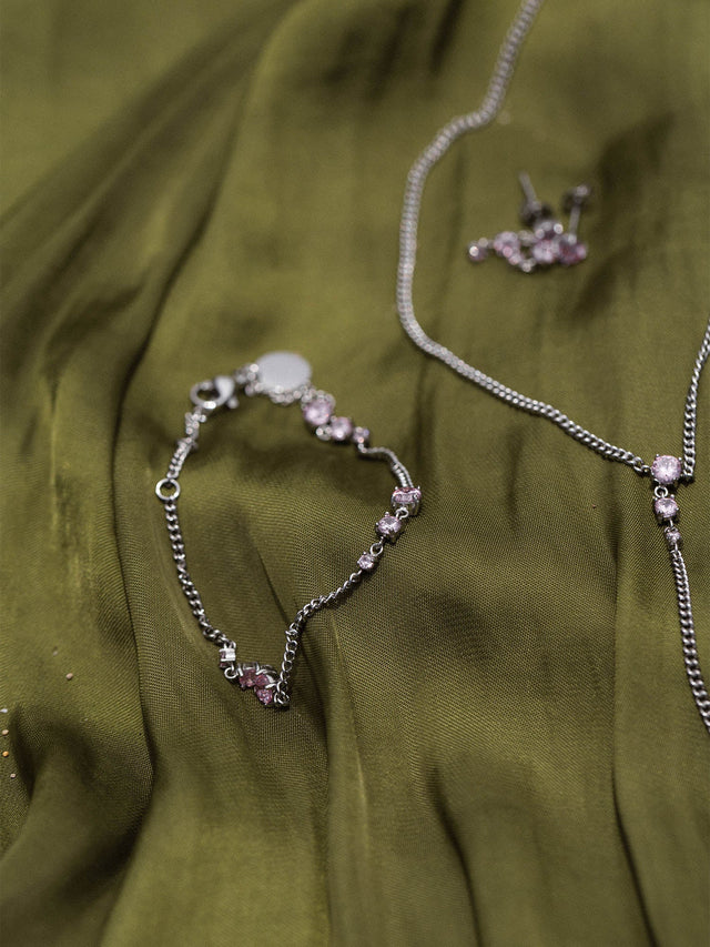 Silberne Kette und Armband auf grünem Stoff, PURELEI inspiriert von Eleganz und Feminität.