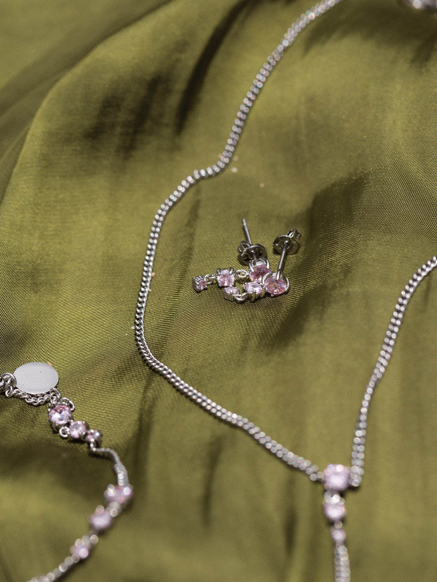 Silberne Kette und Ohrringe auf grünem Stoff, PURELEI inspiriert.