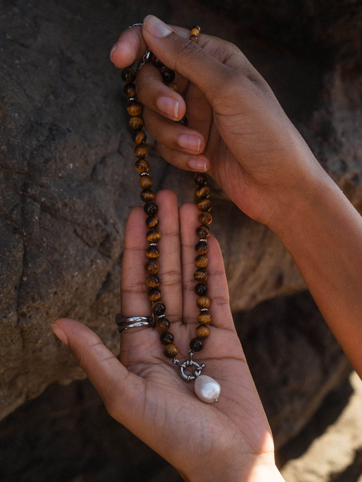 Braune Perlenkette mit Muschel-Anhänger, inspiriert von PURELEI, in warmem Licht gehalten.