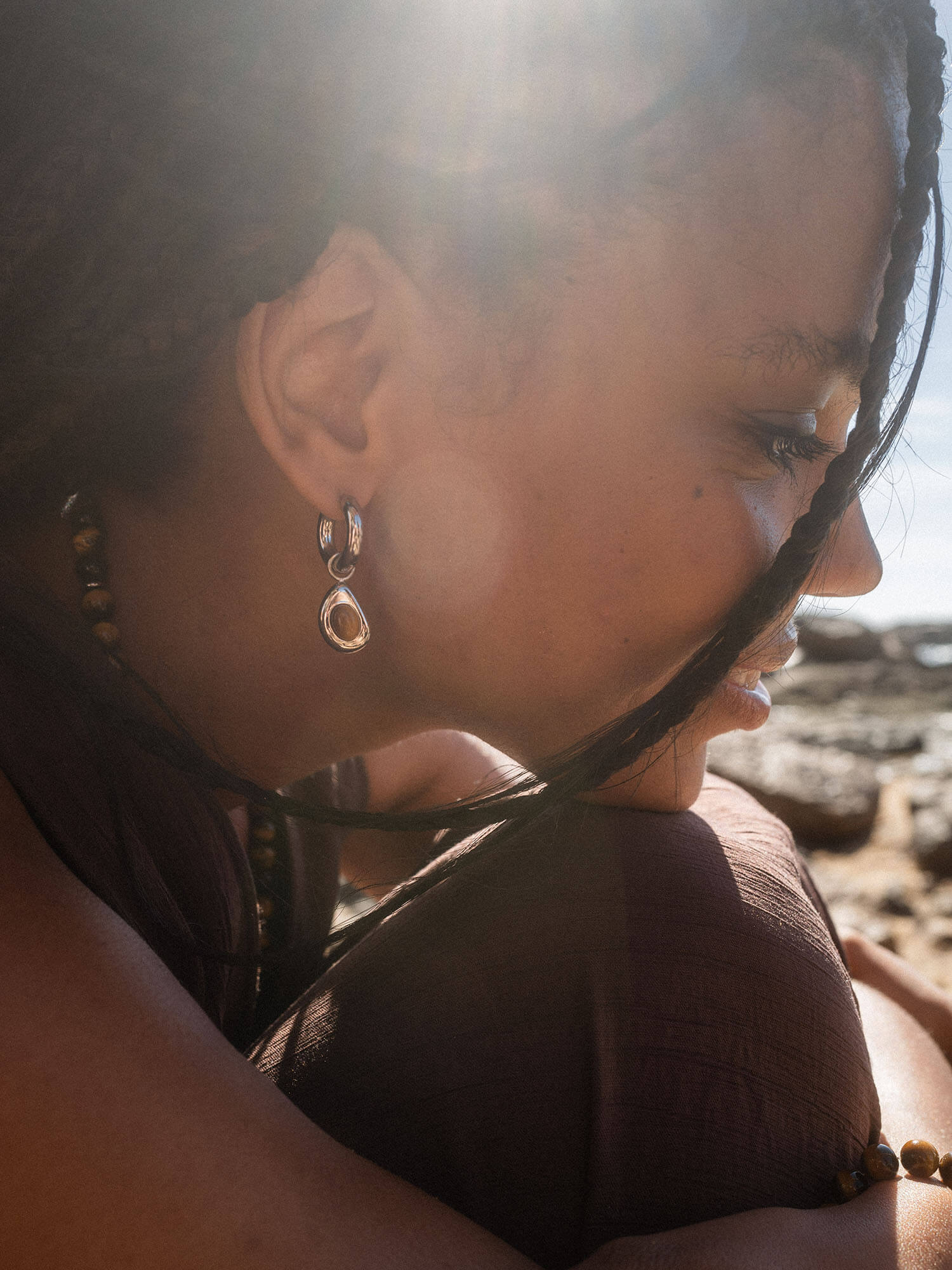 Silberne Ohrringe von PURELEI, elegant und glänzend, getragen in warmem Sonnenlicht.