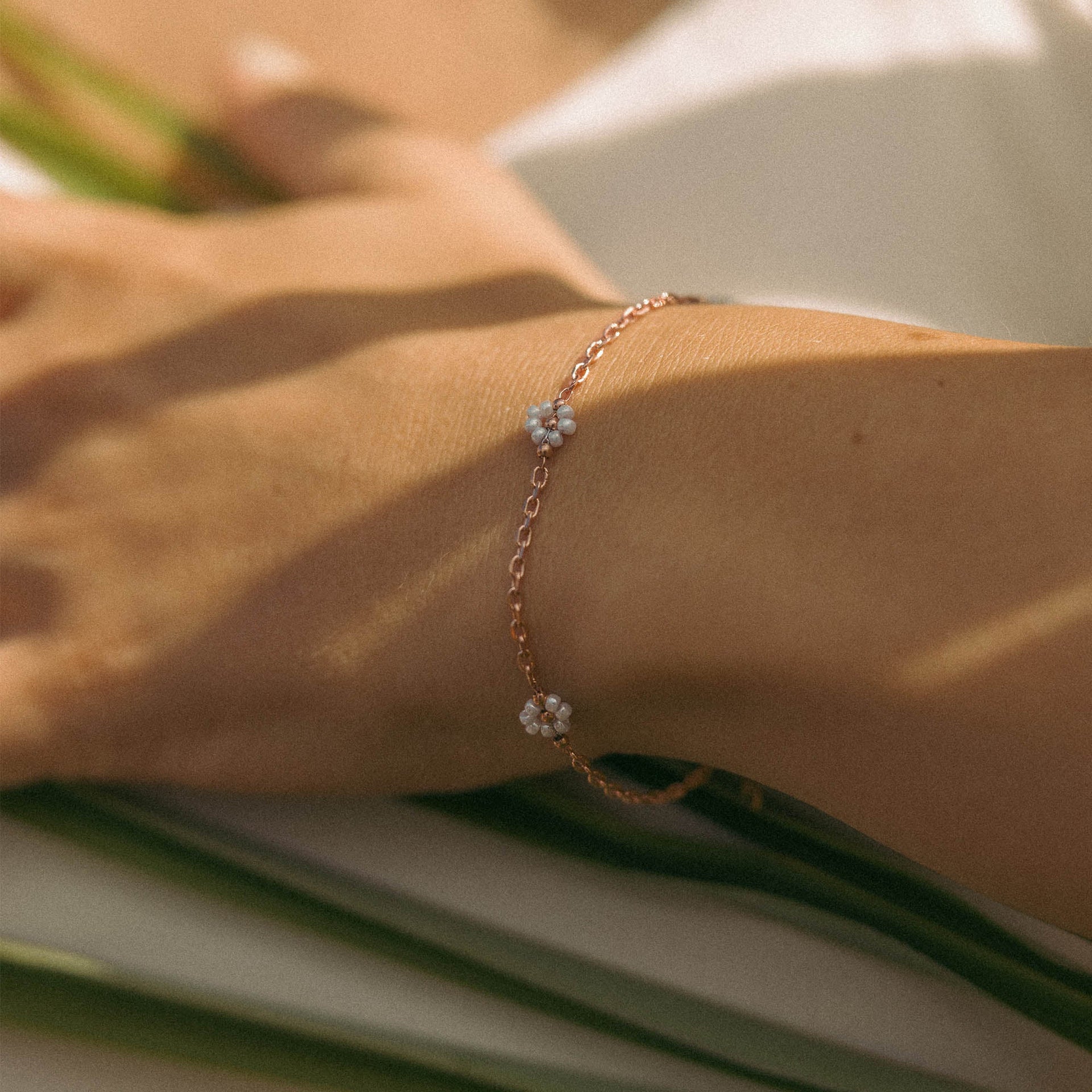Zartes, roségoldenes Armband mit blütenförmigen Details von PURELEI, getragen am Handgelenk.