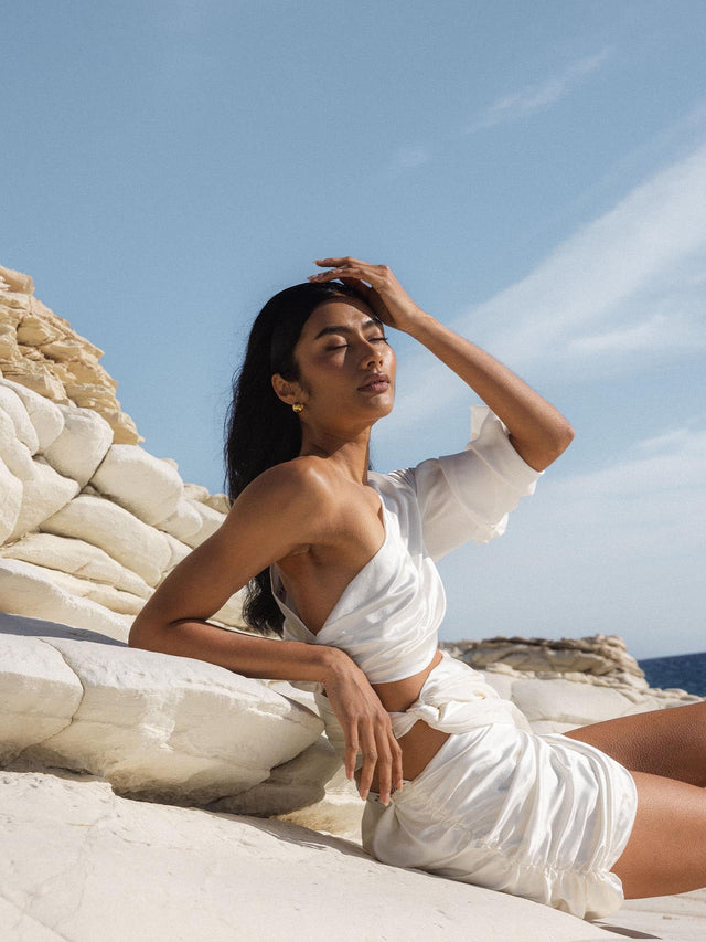 PURELEI Capricorn Letter Charm in 18K Gold, minimalist am Arm getragen, strahlt zeitlose Eleganz und Naturverbundenheit aus.