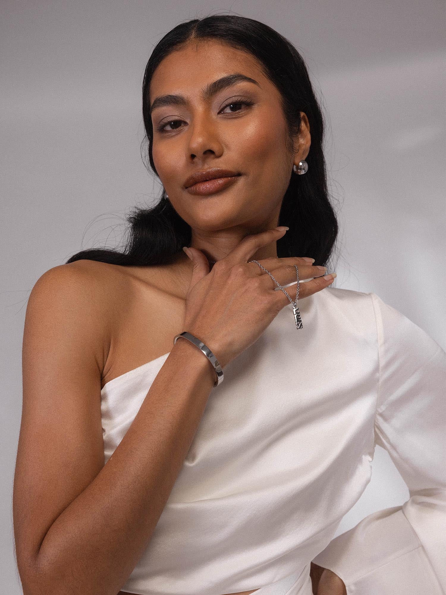 PURELEI Aries Letter Charm in silberner Edelstahl-Optik, modern und elegant am Handgelenk getragen.