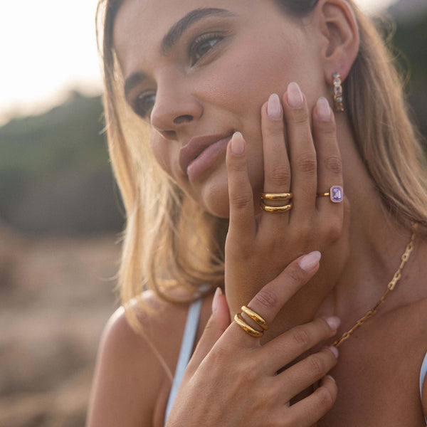 Goldene Ringe und Kette von PURELEI, getragen in warmem Licht, elegant und feminin.