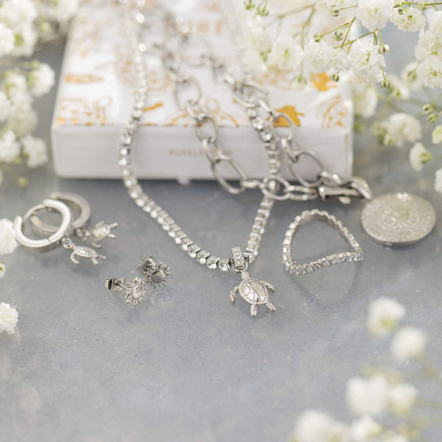 Silberne Schmuckstücke von PURELEI mit Schildkröten- und Sonnenmotiven, elegant arrangiert.