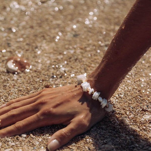 PURELEI Wela Armband mit echten Muschel- und Perlenstücken, wasserfest getragen am Strand in sonniger Atmosphäre