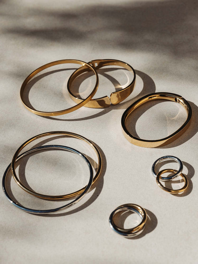 Goldene Ringe und Armreifen von PURELEI auf hellem Untergrund, elegant und modern.