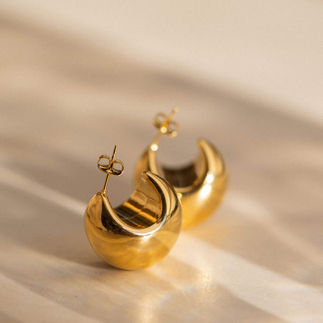 Goldene Creolen mit geschwungenem Design von PURELEI, elegant und modern.