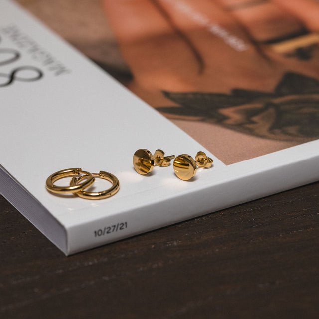 PURELEI Coin Ohrringe aus 18K vergoldetem Edelstahl, minimalistisch und elegant, auf Buchrückseite inszeniert.