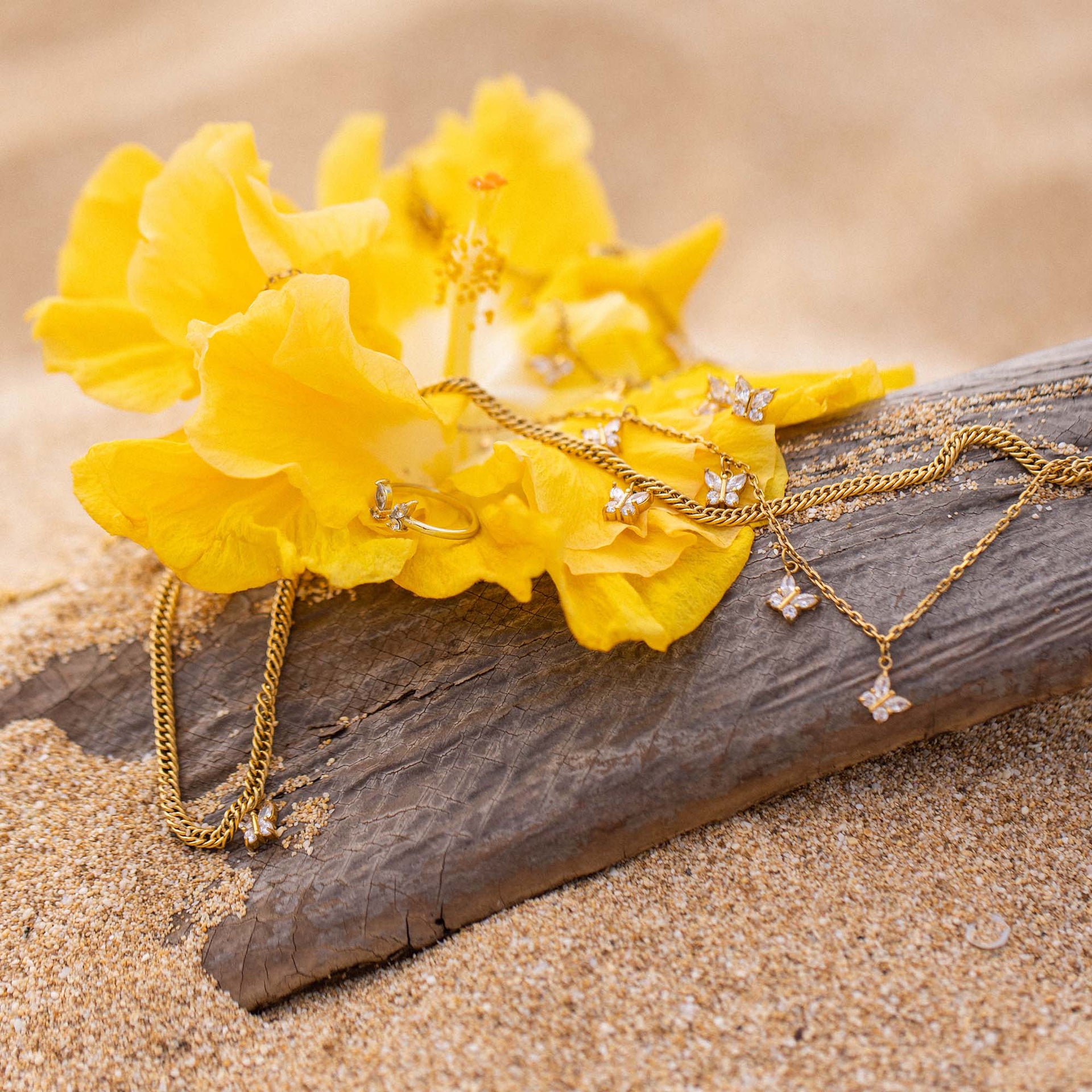 Goldene Kette und Ohrringe auf gelber Blüte, inspiriert von PURELEI.